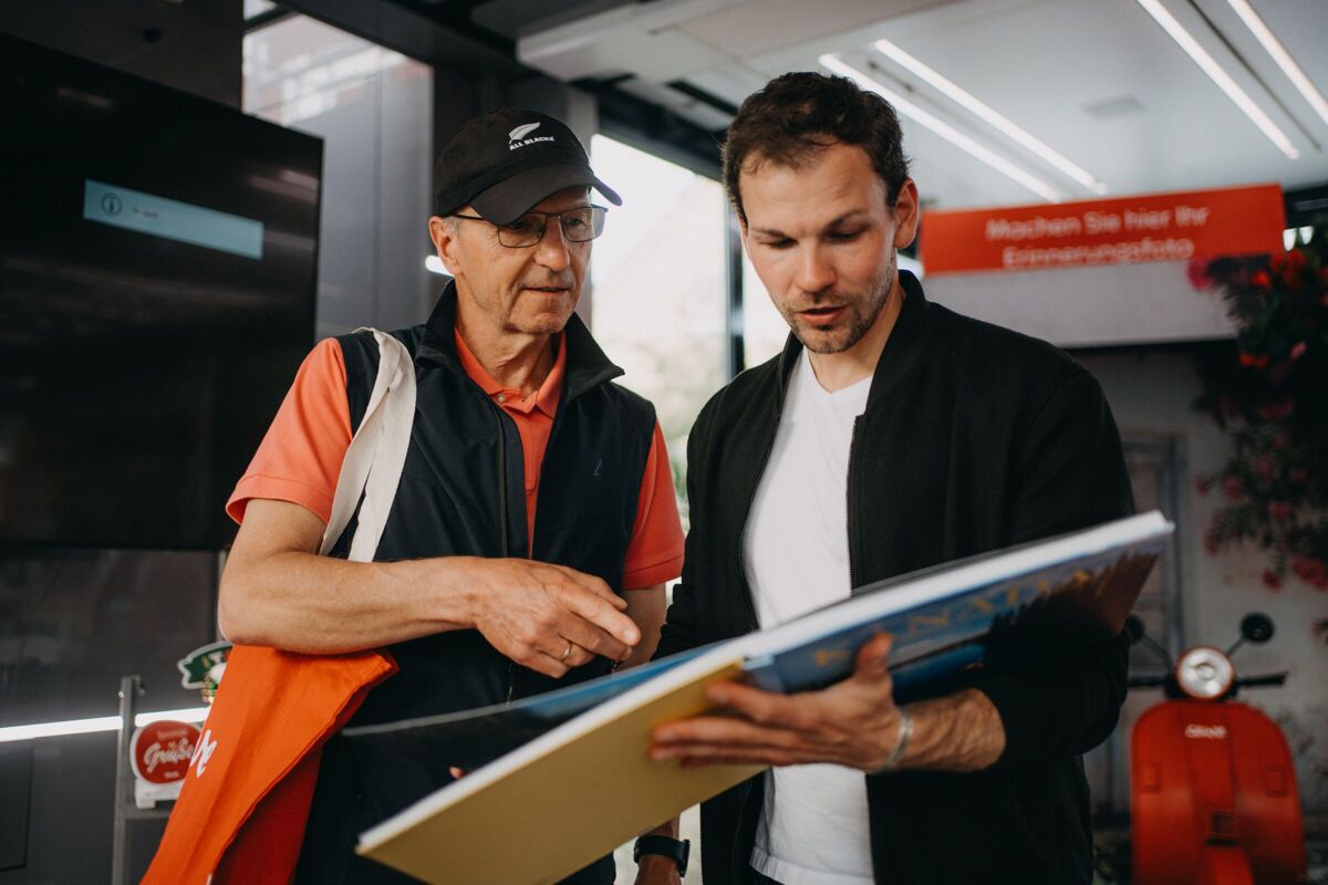 Zwei Männer betrachten gemeinsam ein aufgeschlagenes CEWE FOTOBUCH.
