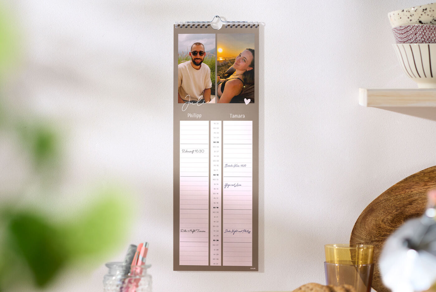An der Küchenwand hängt ein CEWE Wandkalender mit Fotos und Platz für zwei Personen
